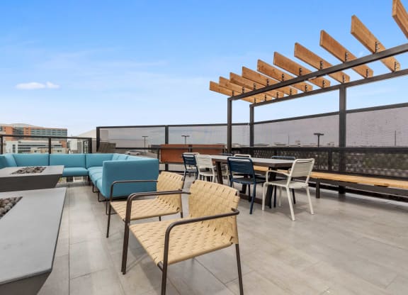 a rooftop patio with tables and chairs and a blue couch
