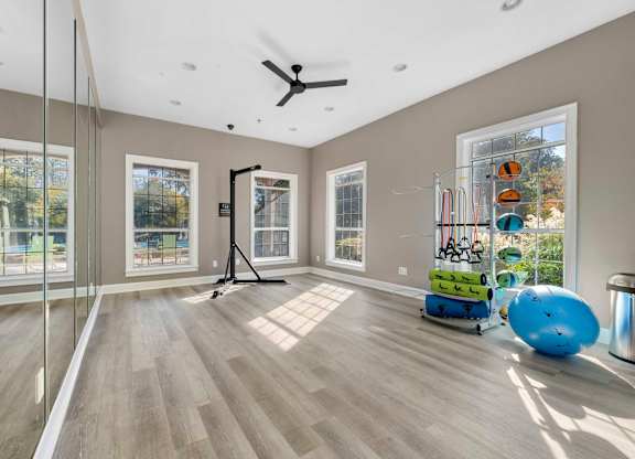 a workout room with mirrors and a ceiling fan