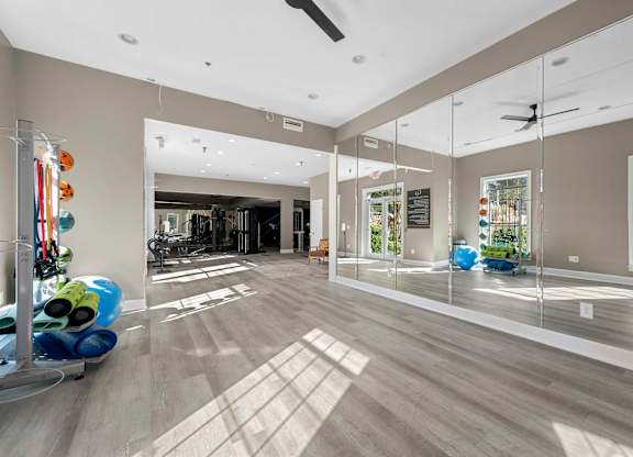 a gym with mirrors in a large room with hardwood floors