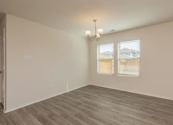 a bedroom with hardwood floors and two windows at The Village at Granger Pines, Conroe