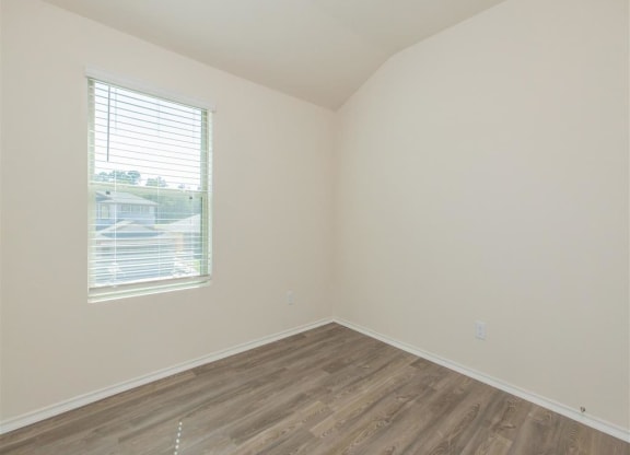 an empty room with a window and wooden floors at The Village at Granger Pines, Conroe Texas