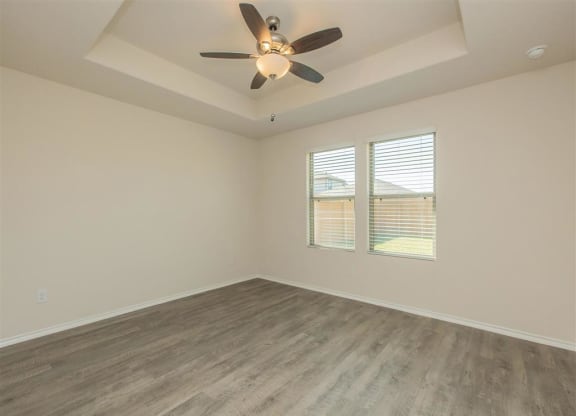 a bedroom with a ceiling fan and two windows at The Village at Granger Pines, Texas, 77302