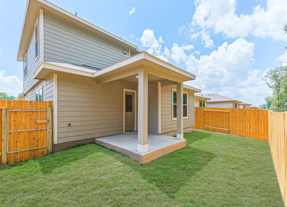 a home with a wooden fence and a green lawn at The Village at Granger Pines, Texas, 77302