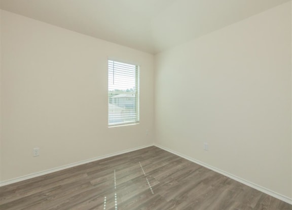 an empty room with a window and a wooden floor at The Village at Granger Pines, Conroe, 77302
