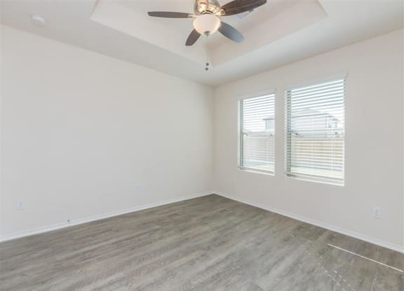 a bedroom with a ceiling fan and two windows at The Village at Granger Pines, Conroe