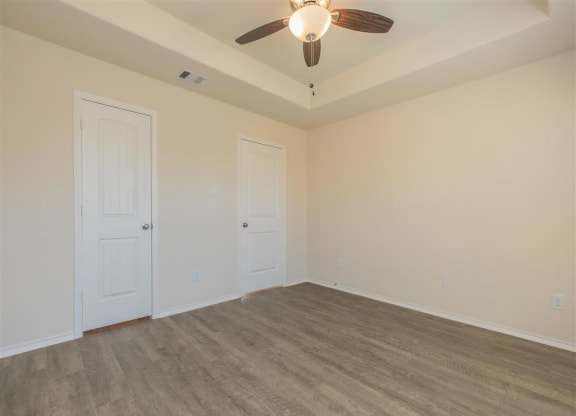 a bedroom with white walls and a ceiling fan at The Village at Granger Pines, Texas