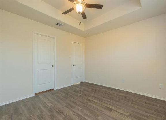 a bedroom with a ceiling fan and a door at The Village at Granger Pines, Texas