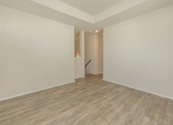a living room with white walls and a wooden floor at The Village at Granger Pines, Texas