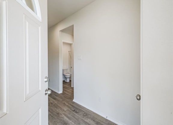 a bedroom with a white door and a bathroom in the background at The Village at Granger Pines, Conroe, 77302