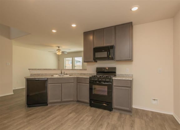 a kitchen with a stove top oven next to a sink at The Village at Granger Pines, Texas