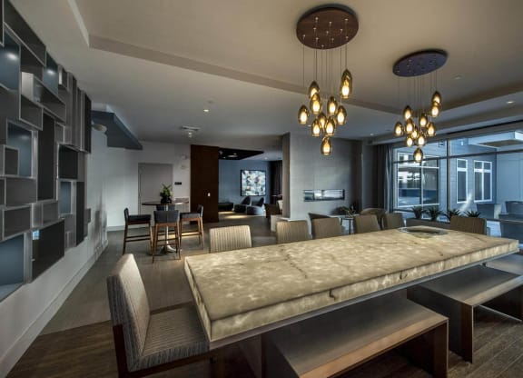 Resident lounge at RE150 Apartments in Medford, MA, featuring a long table surrounded by chairs and modern decor.