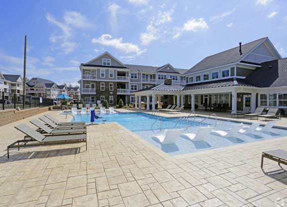 a large swimming pool with lounge chairs and a building in the background