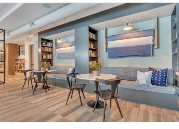 a seating area with tables and chairs and a wall with paintings