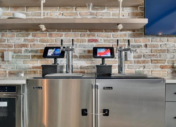 two refrigerators in a kitchen with a brick wall