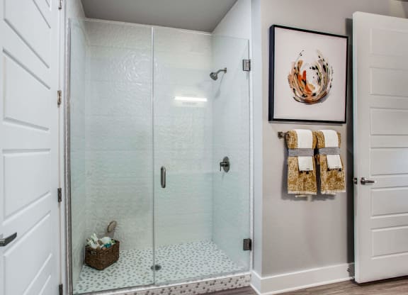 the shower in the master bathroom has a glass door and a tiled floor