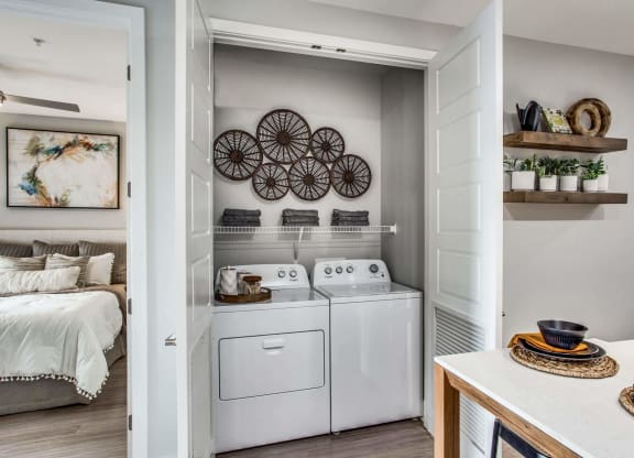 a white washer and dryer in a laundry room with a bed