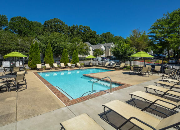 a swimming pool with chairs and umbrellas at the resort on a sunny day