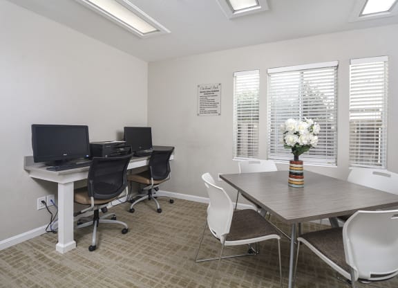 a conference room with three computers and a table and chairs