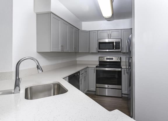 a kitchen with white counter tops and stainless steel appliances