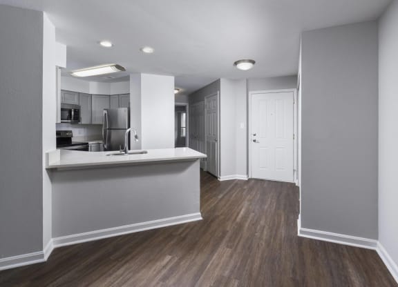 an empty apartment with a kitchen and a door to a hallway