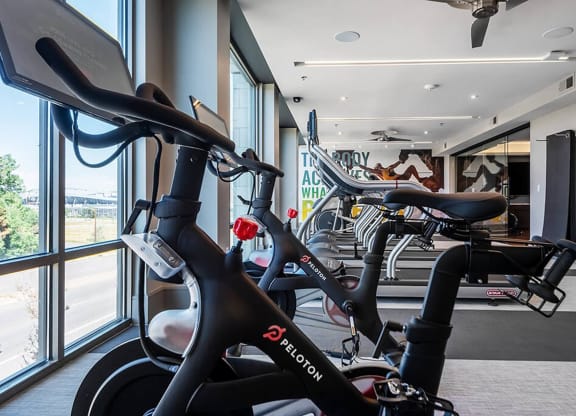 a gym with several bikes in a room next to a window