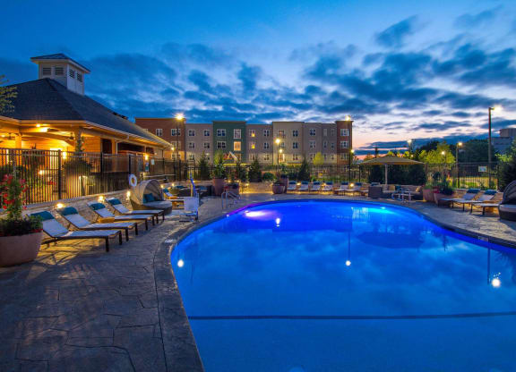 a swimming pool at night with a hotel in the background