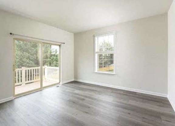 an empty living room with wood floors and a balcony