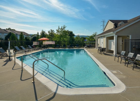 a swimming pool with chairs and a building with a house