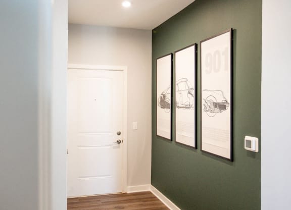a hallway with a white door and three pictures on the wall