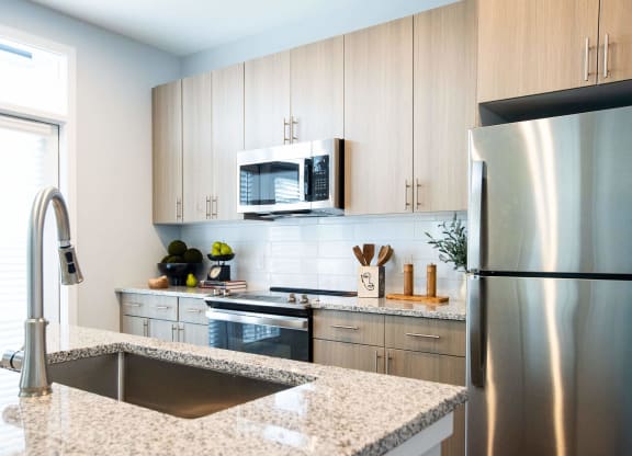 a kitchen with white cabinets and marble counter tops