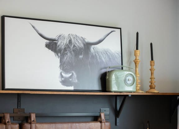 a painting of a cow on a shelf with a radio and a phone