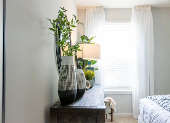 a bedroom with a table with vases and plants on it