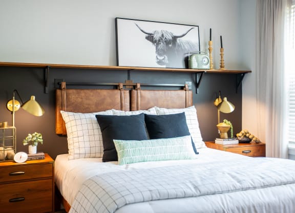 a bedroom with a bed with a wooden headboard and a painting of a bull