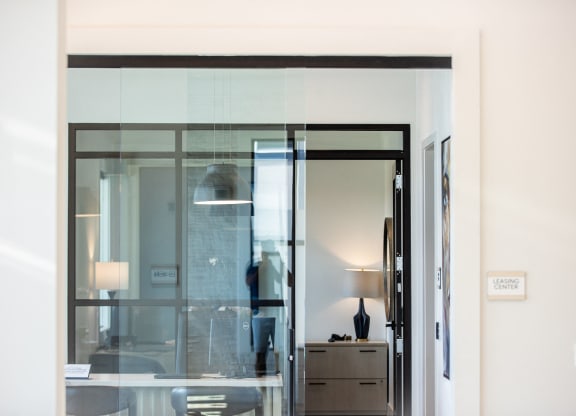 a glass door in a room with a desk and a lamp