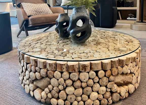 a coffee table made out of logs with two black vases on it