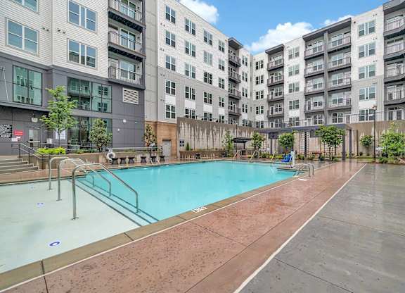 an apartment swimming pool with an apartment building in the background
