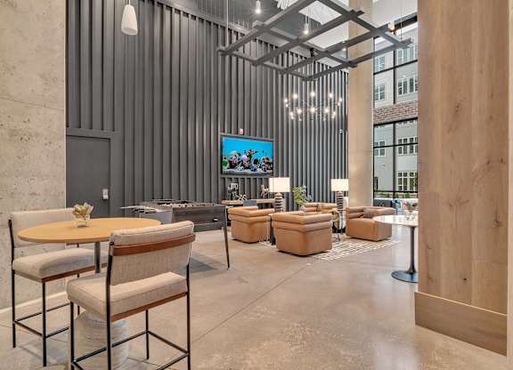 a lobby with chairs and tables and a tv