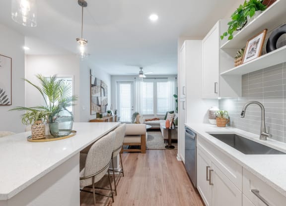 an open kitchen and living room with white cabinets and a sink