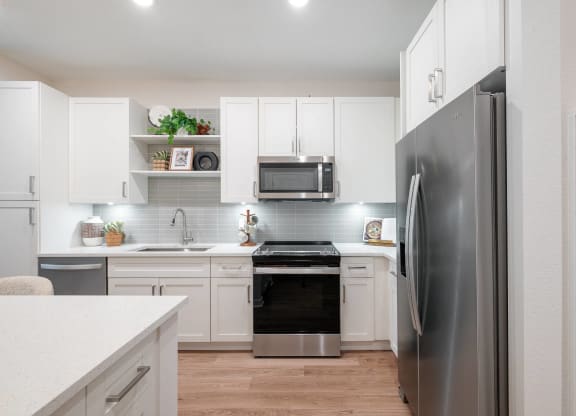 a white kitchen with stainless steel appliances and white cabinets