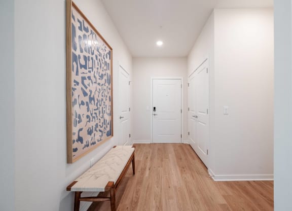 a hallway with a bench and a painting on the wall and white doors