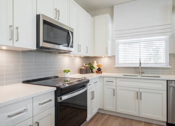 a kitchen with white cabinets and a stove and a microwave