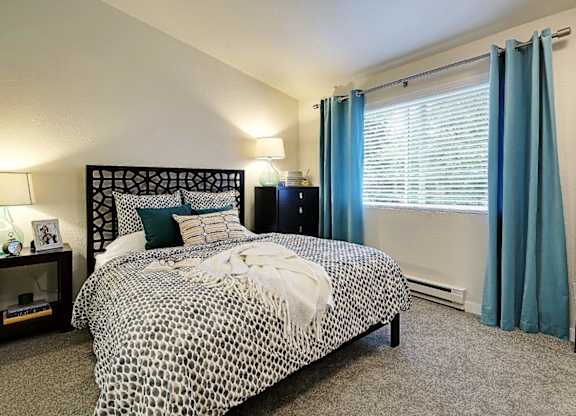 Bedroom with decorative headboard and patterned bedding at Hidden River Townhomes Apartments, Kirkland, 98034