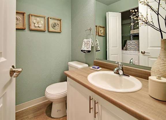 Guest bathroom with white vanity and sage green walls at Hidden River Townhomes Apartments, Kirkland, Washington