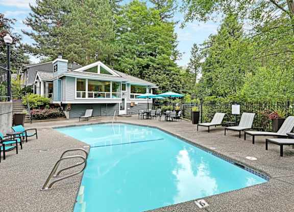 Outdoor swimming pool with lounge chairs and cabana at Hidden River Townhomes Apartments, Kirkland