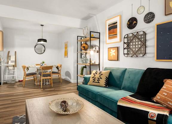 Open concept living and dining area with teal sofa at Scout Apartments, Washington