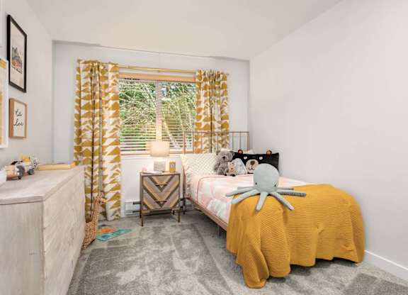 Childs bedroom with yellow bedding and patterned curtains at Scout Apartments, Washington