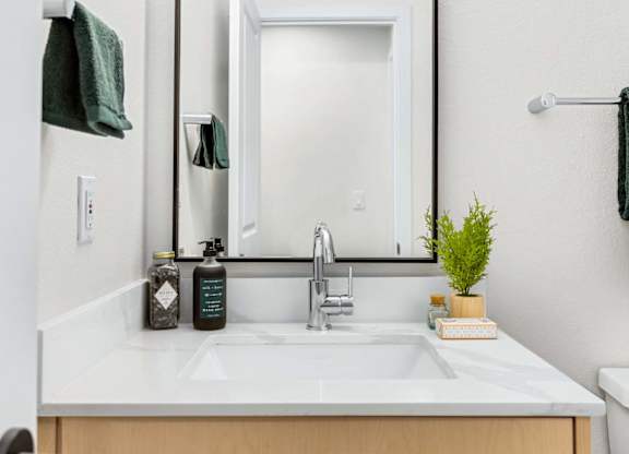 Bathroom vanity with white countertop and framed mirror at Scout Apartments, Kirkland, WA