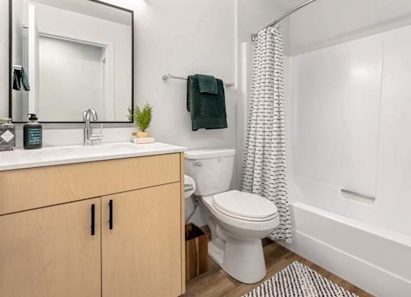Bathroom with white tub and shower curtain at Scout Apartments, Washington