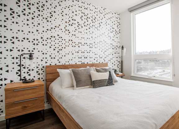 A bedroom with a bed, nightstand, and a wall with a black and white geometric pattern.at Axle, Seattle 