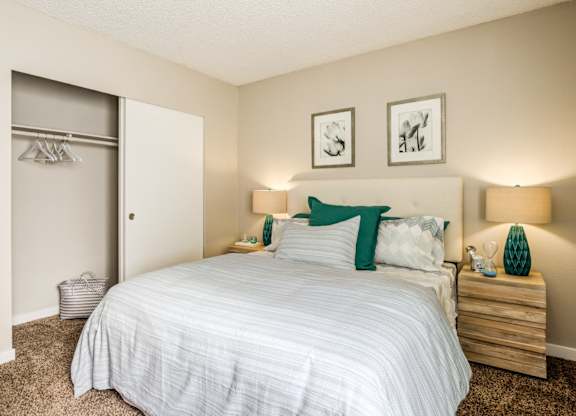 A bedroom with a bed, nightstands, and two pictures on the wall.